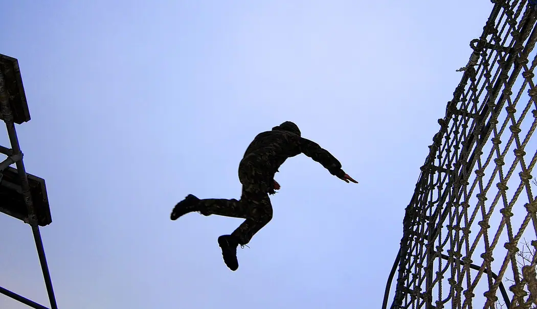 British Army soldier jumping from a platform toward a training cargo net